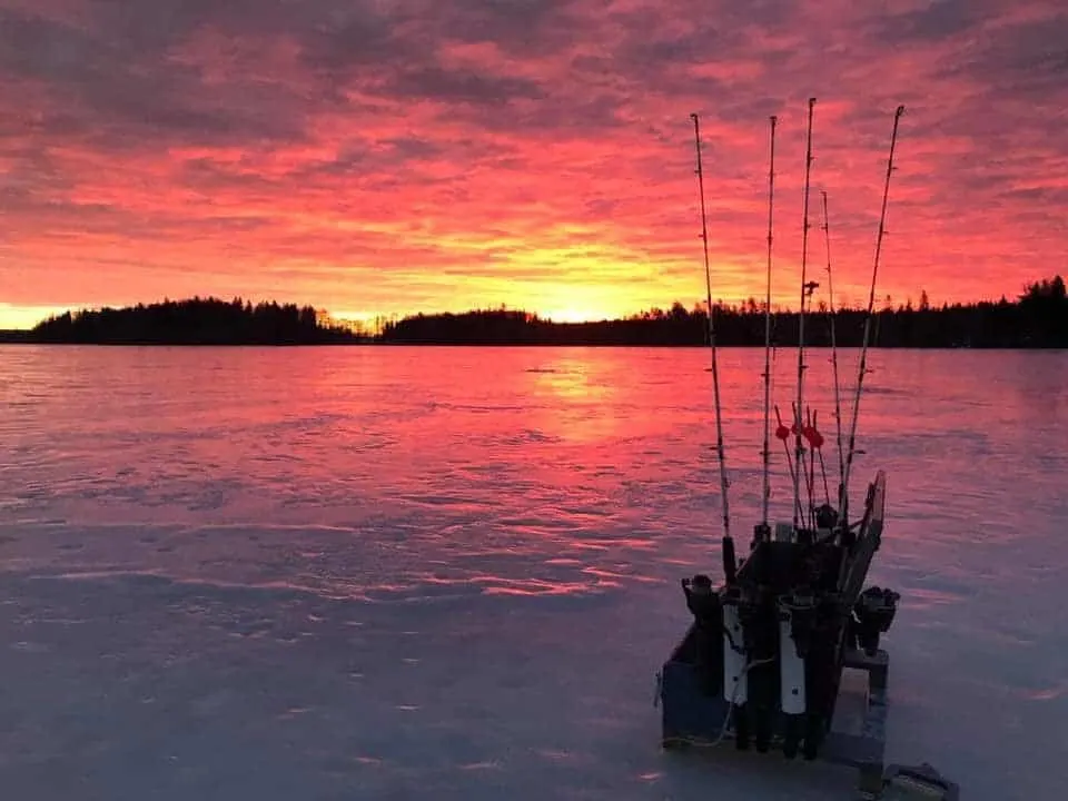 a sunrise over an iced pike fishing lake in the middle of winter