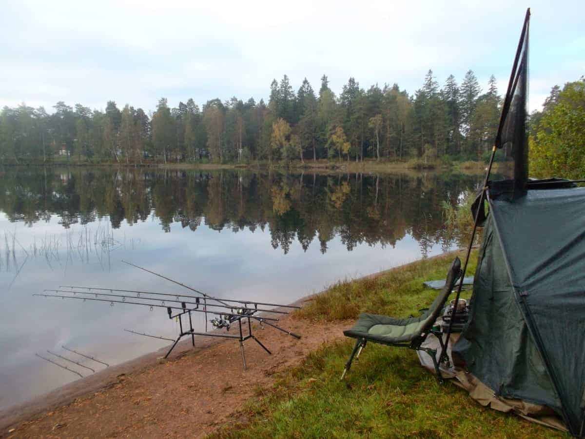 a picture of a fishing tent and gear on a lake bank