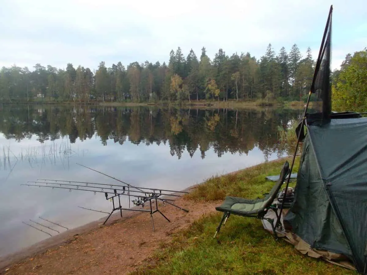 a picture of a fishing tent and gear on a lake bank