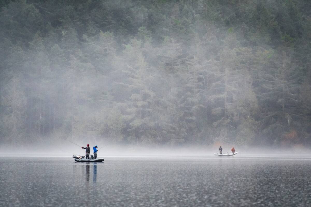 Anglers on boats on a lake who are fishing in the rain