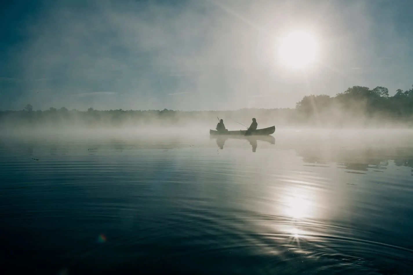 two anglers in a boat fishing on a lake at sunrise