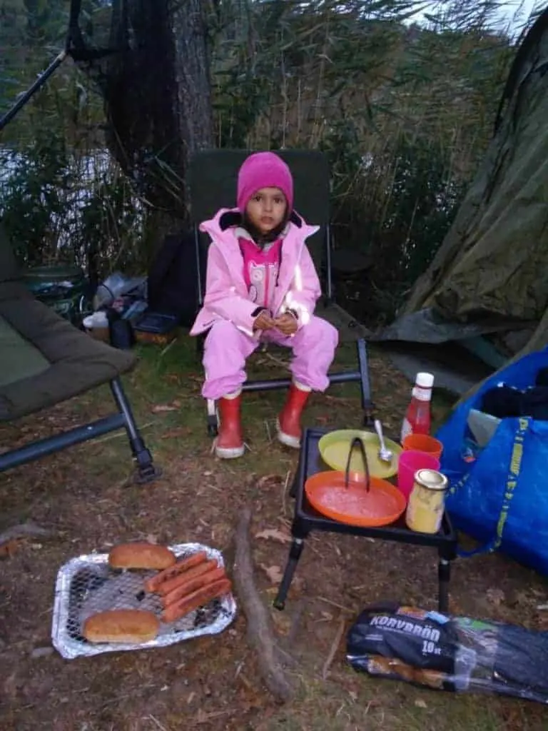 a young angler fishing with her dad and eating some eveing hot dogs