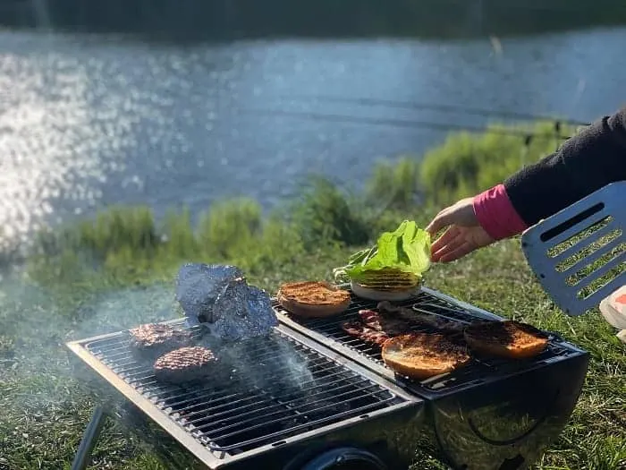 a couple of delicious hamburgers being prepared during a fishing trip