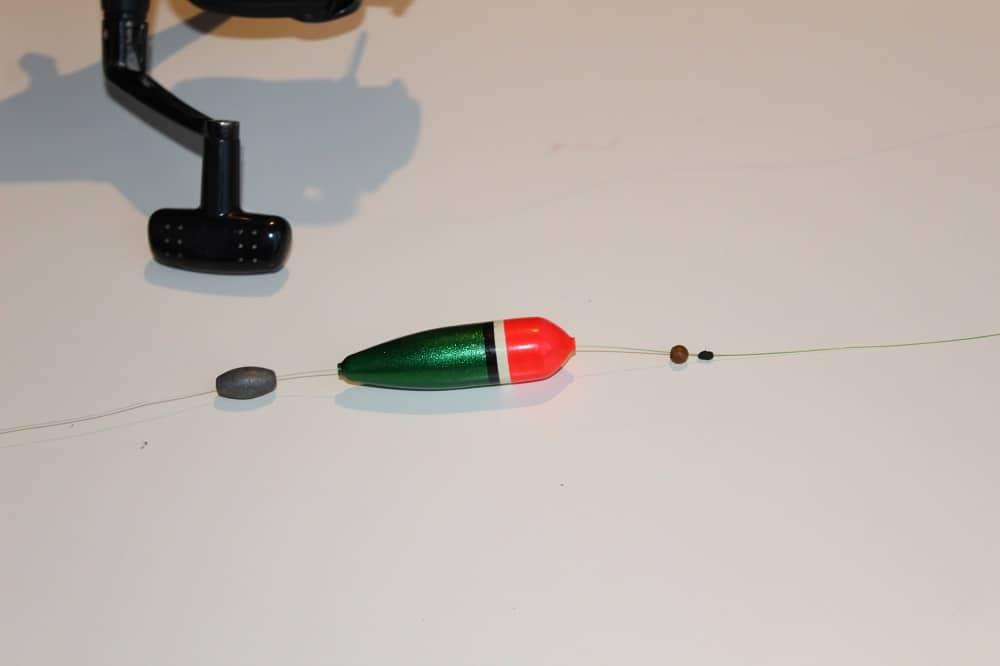  une image d'un morceau de ligne de pêche avec un arrêt de bobber, une perle d'arrêt, un plomb et un bobber de glissement dessus 