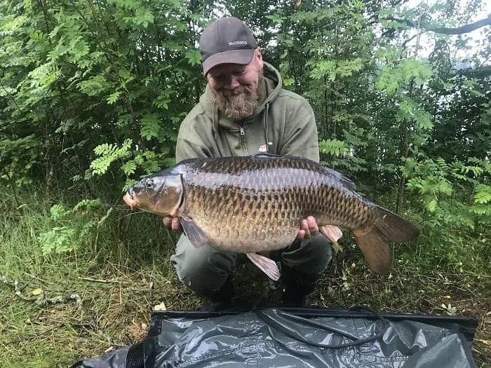 a fisherman holding a fat common carp