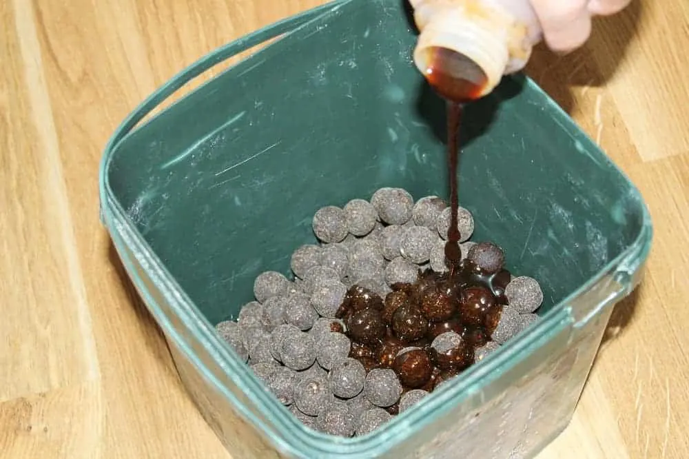 thick boilie glug being poured over some boilies in a bucket