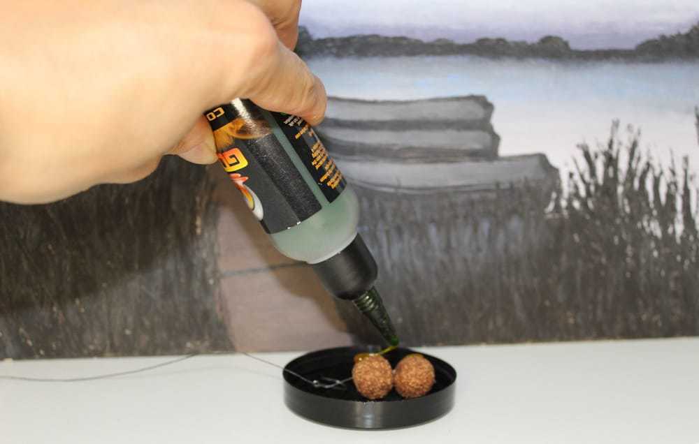 a carp bait goo being applied to two boilies on a hair rig