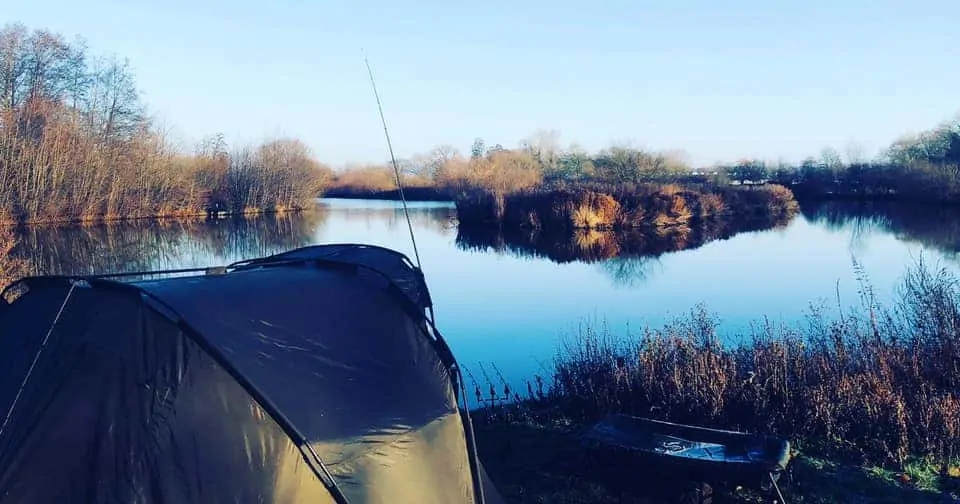 an image of a carp bivvy and a rod by a lake in winter