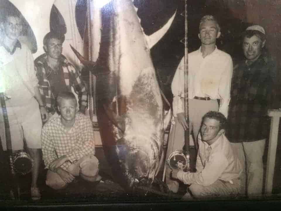 an old image of a group of men with a big bluefin tuna catch