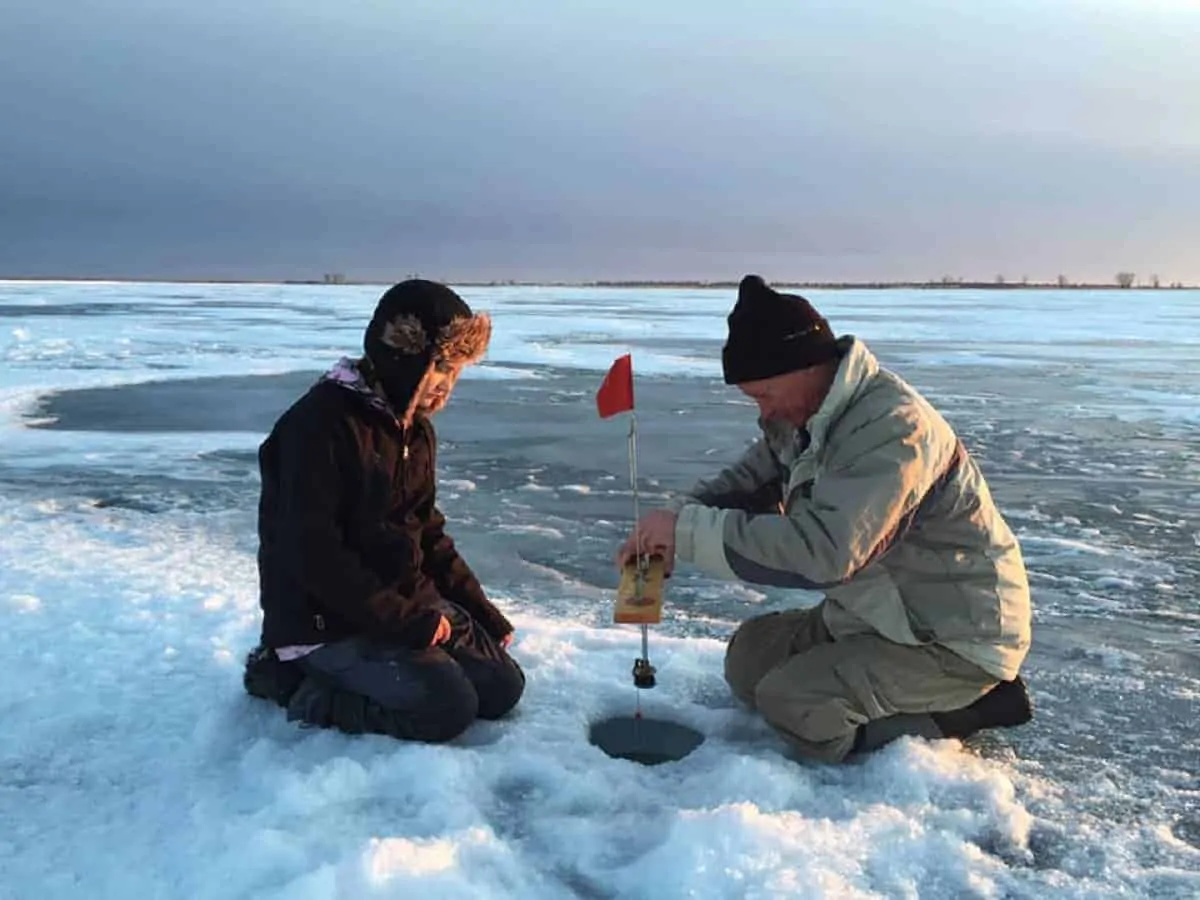 two ice anglers preparing a tip up for pike fishing through the ice