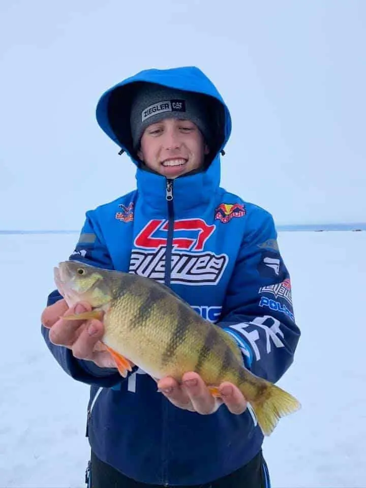 a young ice angler on a frozen Minnesota lake with a nice yellow perch