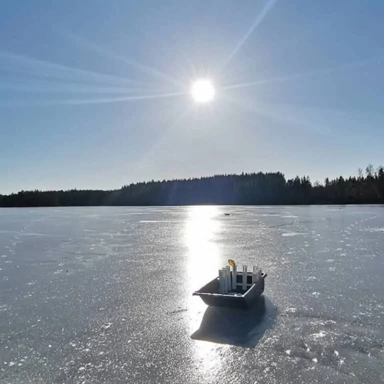 a picture of a frozen lake with an ice fishing sled with fishing gear on it