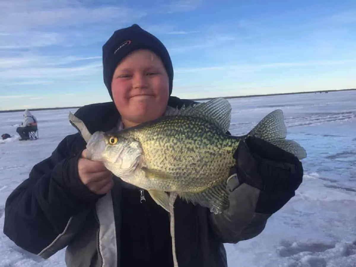a young fisherman on a frozen Minnesota lake holding a nice crappie