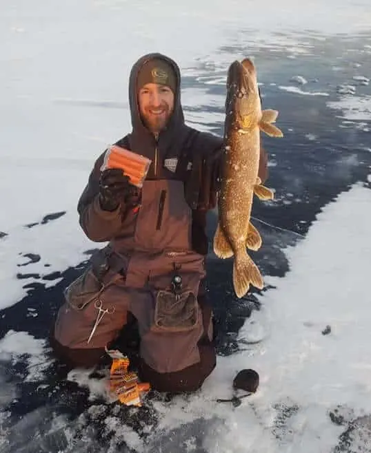 an ice angler with a northern pike caught on a hot dog