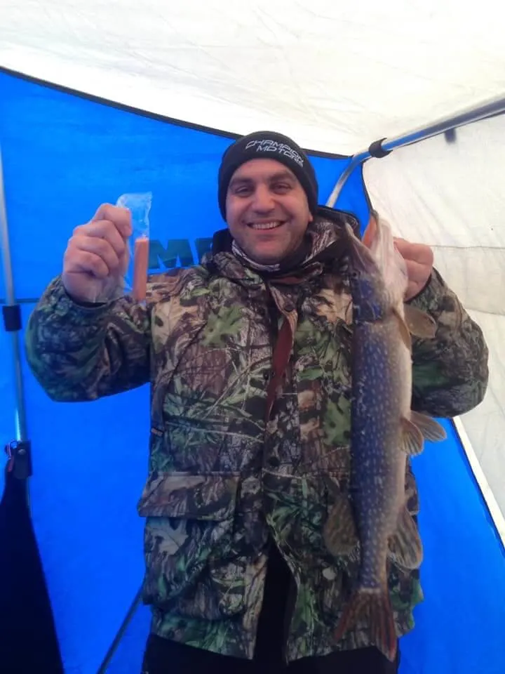 a happy angler ice fishing for pike with hot dogs