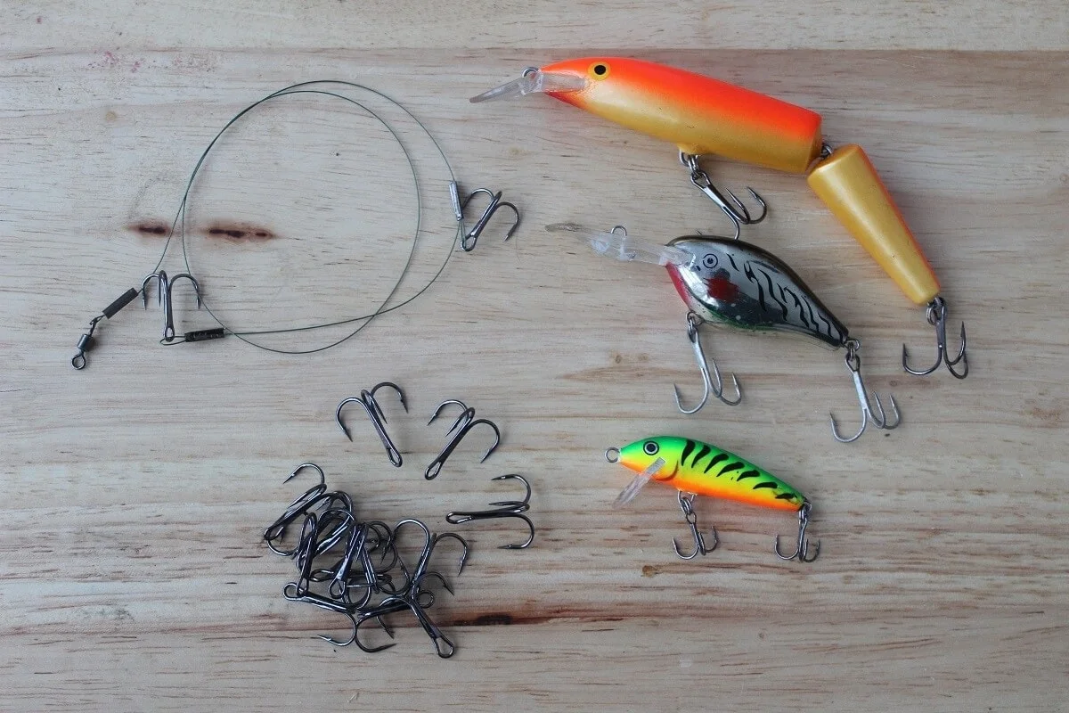 treble hooks for lures and wire leaders for predator fishing displayed on a table together with some crankbaits and a quick strike rig.