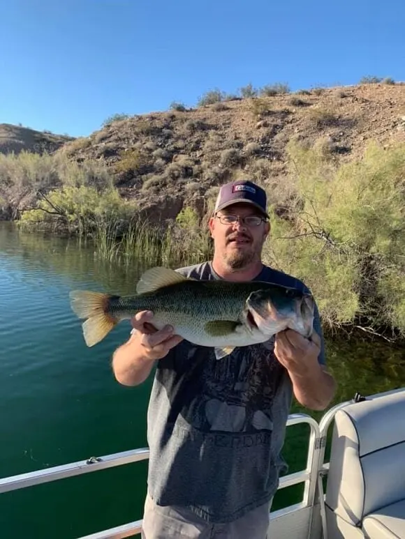 a happy bass angler holding a big largemouth bass on a boat