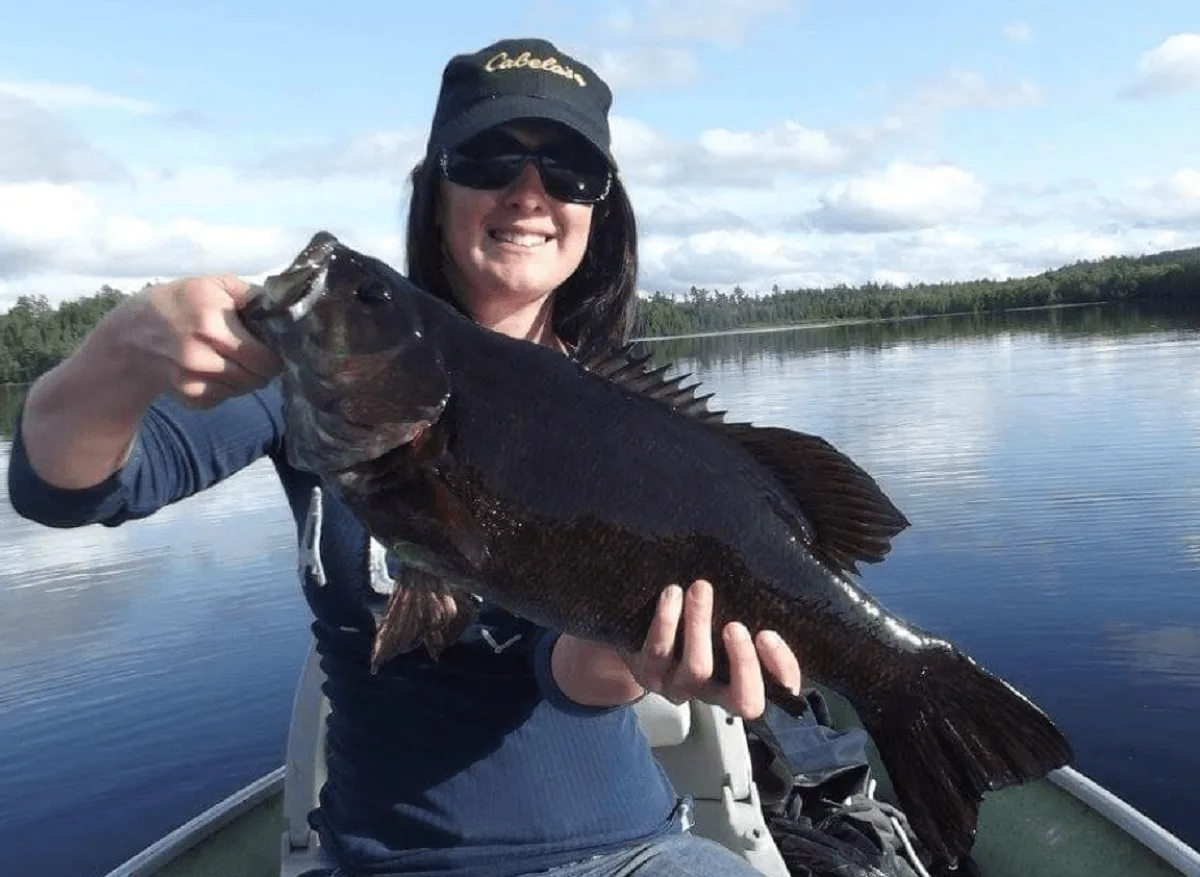 a female angler holding a big bass that she has caught on a wire leader and a softbait.