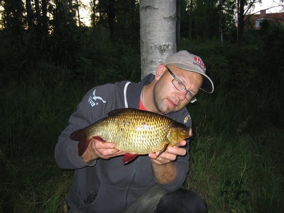 a fisherman holding a big rudd that he has caught on the feeder rod at night