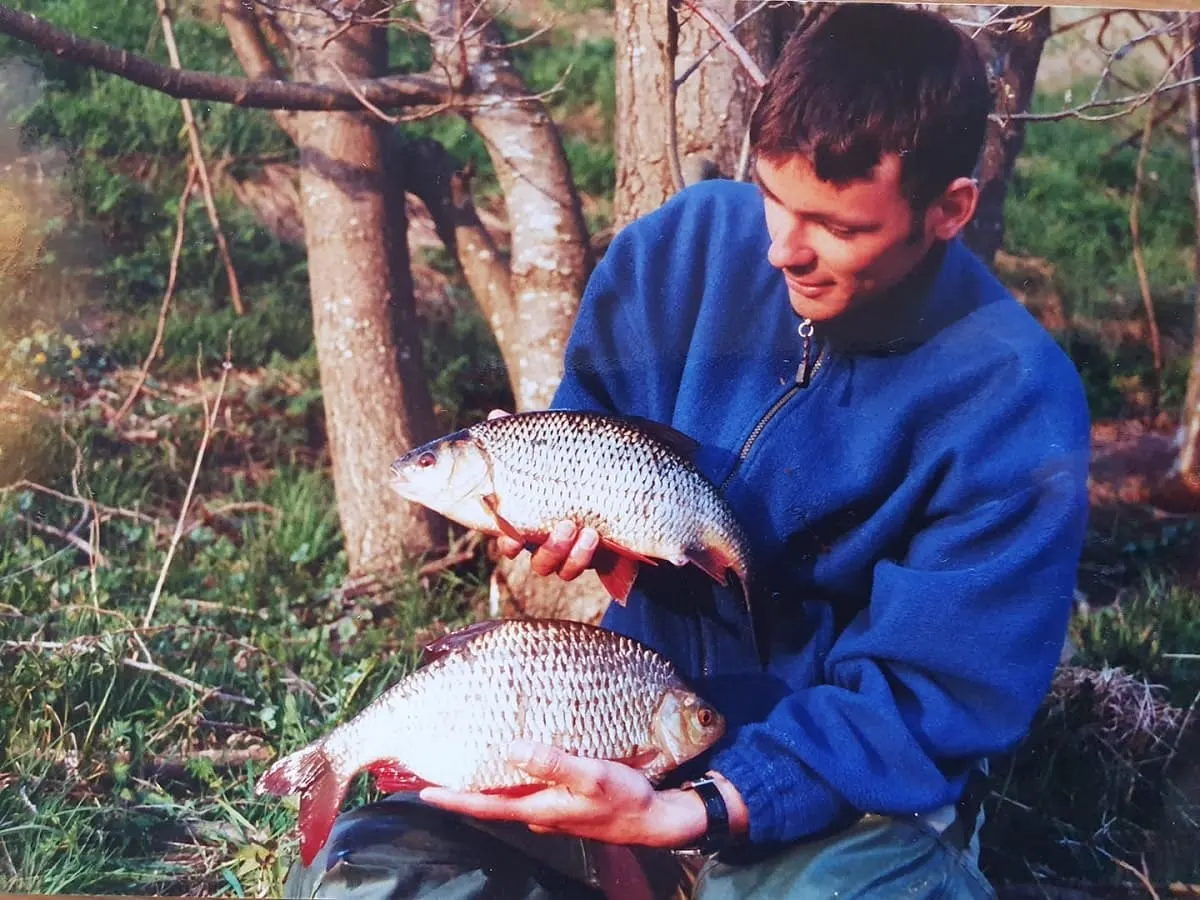 a specimen angler holding a big roach and a big rudd that he has caught on the feeder rod in a lake