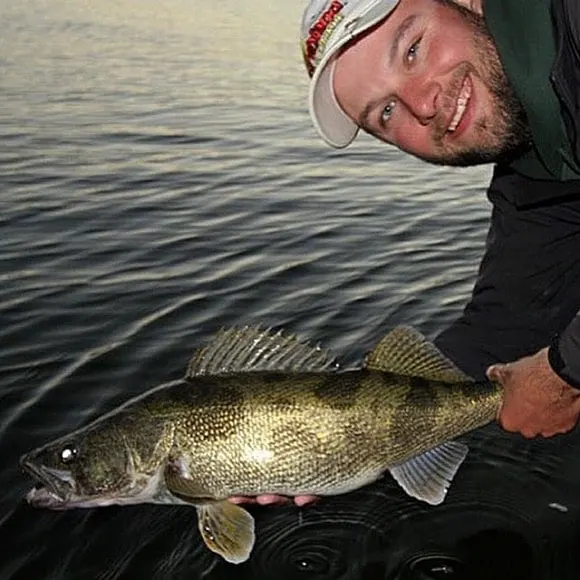 a happy angler on a boat releasing a big saugeye that he has caught while spin fishing