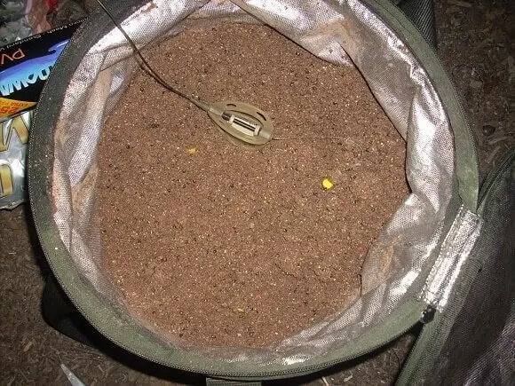 a bucket of bream groundbait with a method feeder rig and a small pop-up on it