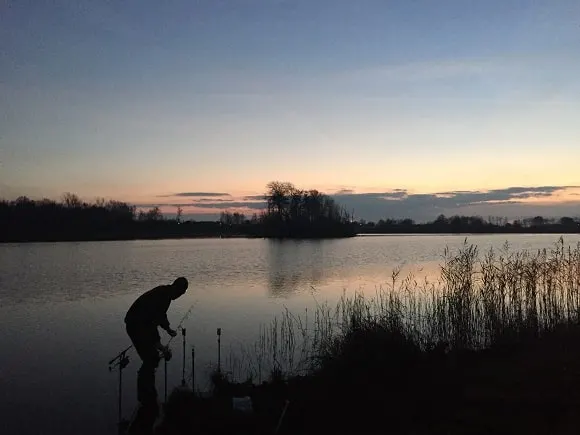 a carp angler adjusting his rods while fishing in a Swedish carp lake