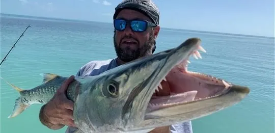 a fisherman holding a giant barracuda that he has caught on a crankbait