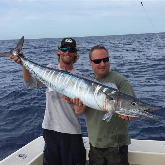 two happy saltwater anglers on a boat on the ocean off Miami holding a nice wahoo