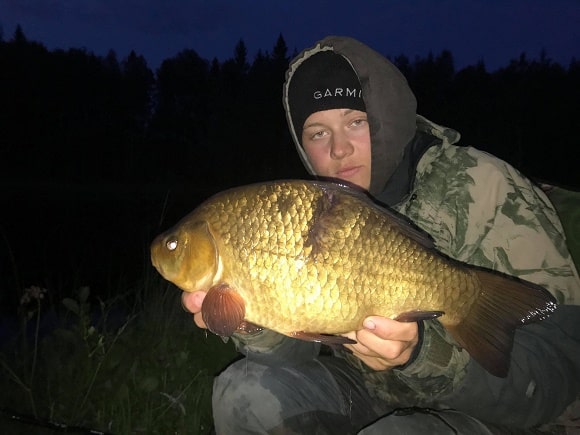 a coarse angler with a big specimen crucian carp that he has caught on the lift method at night