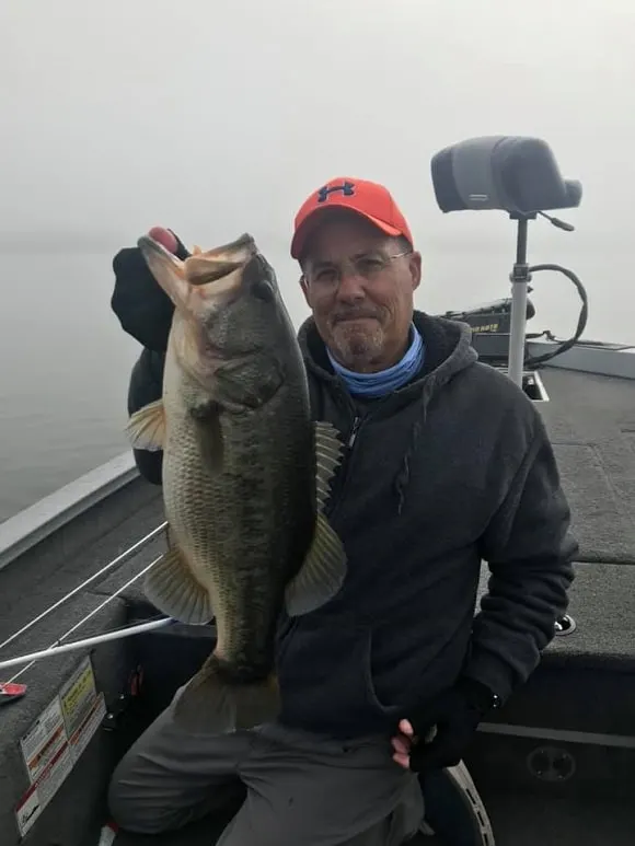a happy bass angler on his boat with a really big largemouth bass caught on a fluorocarbon leader and a softbait