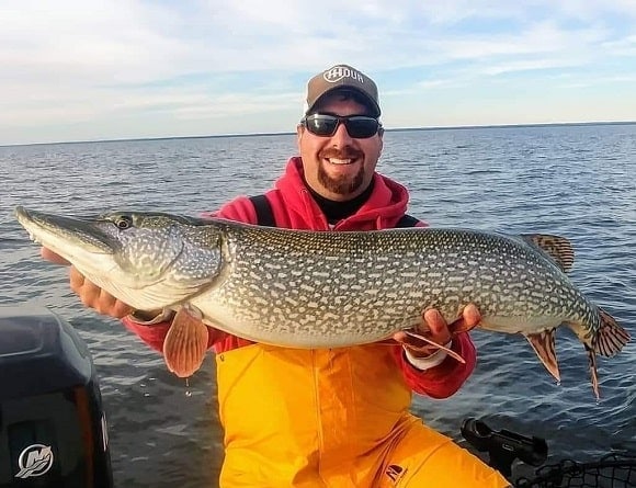 a fisherman on his boat with a giant northern pike