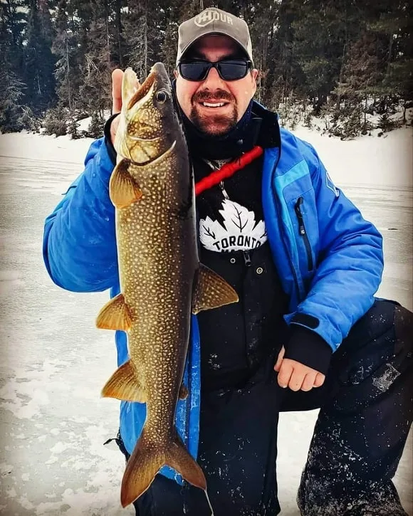 an ice angler on a frozen lake with a nice lake trout