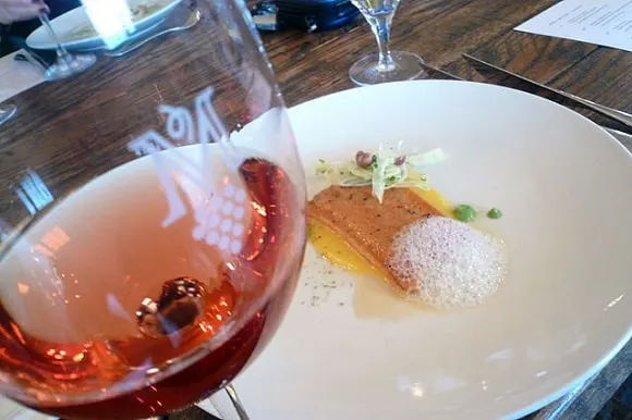an image of a steelhead fillet on a plate next to a glass of rosé wine