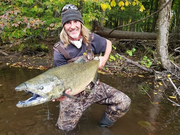 a US angler on a river holding a huge king salmon 