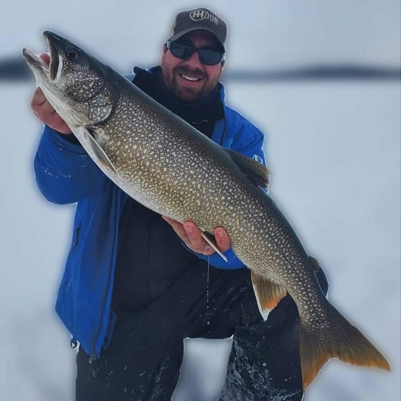 an angler ice fishing on lake simcoe holding a giant lake trout