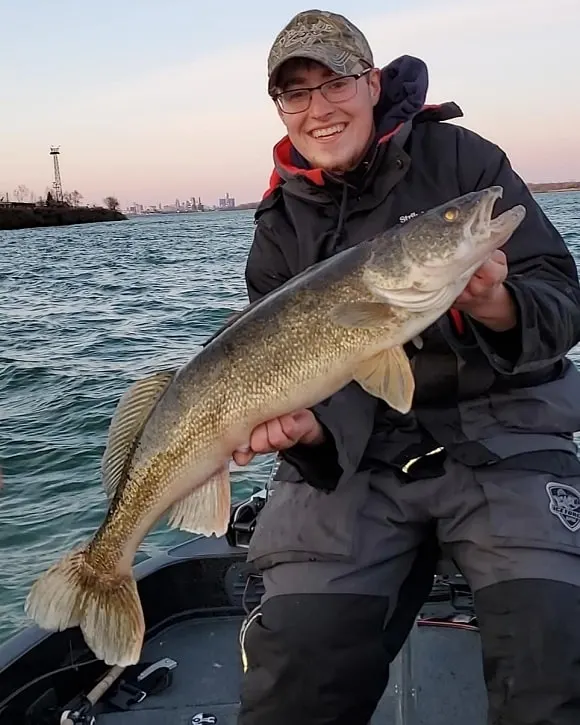 a happy fisher holding a big walleye that he has caught on the Detroit River