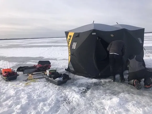 two ice anglers preparing their pop-up shelters and ice fishing equipment on lake simcoe