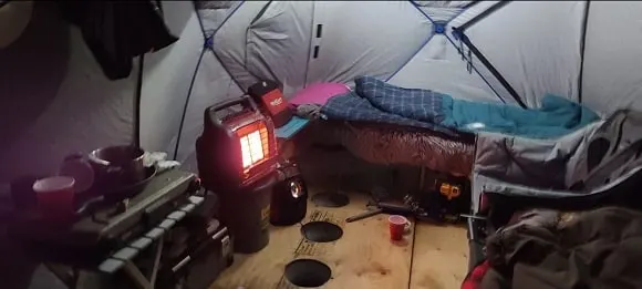 a permanent ice house with a bed and a mr heater buddy for warmth