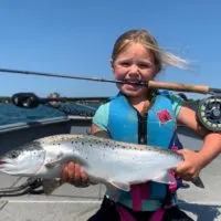 a young angler on a boat holding a big landlocked Atlantic salmon