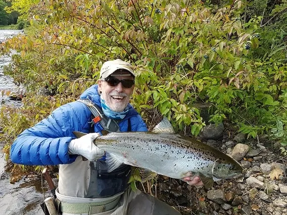 a US angler on a river holding a big landlocked Atlantic salmon