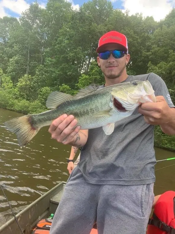 an angler holding a nice bass that he has caught in muddy water conditions