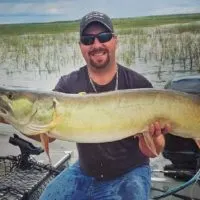 a happy predator angler holding a giant stained water musky