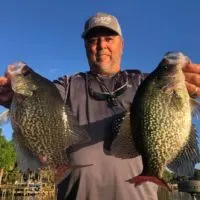 a US angler on his boat holding two big crappies