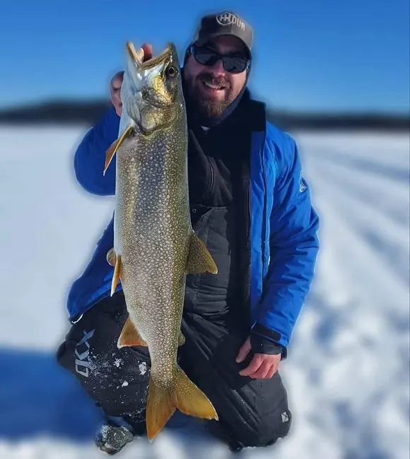 a happy ice angler on a frozen lake holding a big lake trout