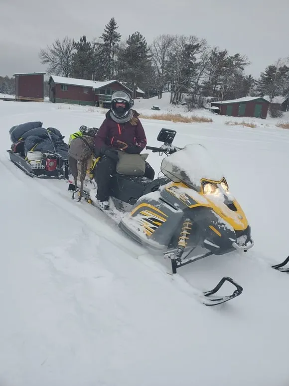 a female angler sitting on a snowmobile on lake of the woods