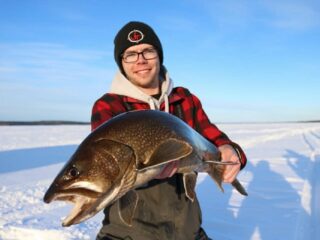 a US ice angler on a frozen lake with a nice lake trout