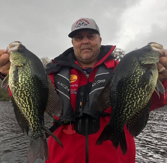 a fisher on his boat holding two huge crappie caught on a jig and a thin fluorocarbon leader