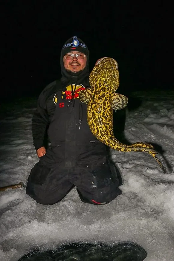 a fisherman ice fishing for burbot at night on lake nipissing