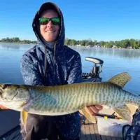 a happy angler on his boat with a beautiful clearwater muskie